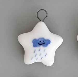 Detail of star-shaped pendant featuring blue smiling cloud pattern on polished white resin