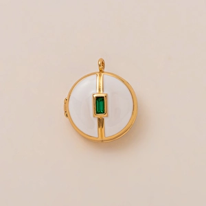 Detail van een vintage medaillon met wit email en een groene smaragd-edelsteen