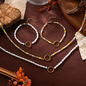Ensemble collier et bracelet en perles avec fermoirs anneaux dorés sur fond rustique