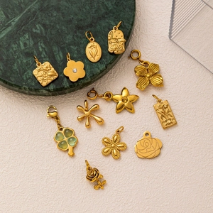 Collezione di ciondoli a fiore e quadrifoglio dorati su marmo con finitura oro 18 carati