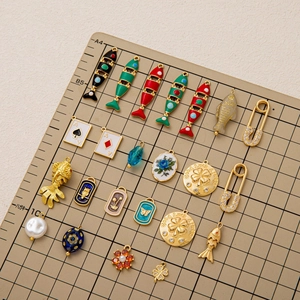 Collezione di ciondoli placcati oro 18K con pesce smaltato e quadrifoglio su tappeto