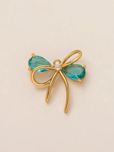 Detailed view of 18K gold bow pendant featuring blue teardrop stones and crystals