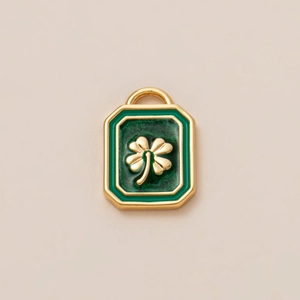 Macro detail of 18K gold plated clover pendant with green enamel inlay for jewelry making