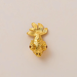Dettaglio di ciondolo a forma di pesce placcato oro 18K con squame e pietre rosse incastonate