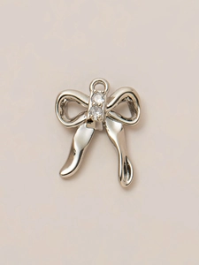 Macro shot of silver bow pendant with clear zircon stones for DIY jewelry making
