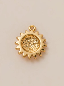 Macro detail of 18K gold plated sun pendant featuring hammered texture and sunburst rays