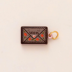 Detail of 14K gold envelope pendant with SEEDS text and orange floral painting