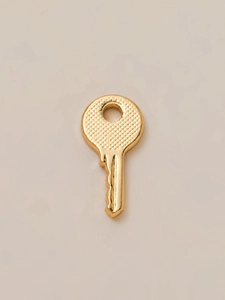 Detailed macro shot of a golden key pendant with textured grip and 18K plating