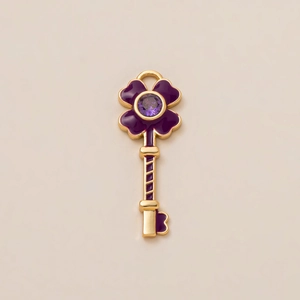 Detail view of a 18K gold-plated clover key pendant with purple enamel and zircon