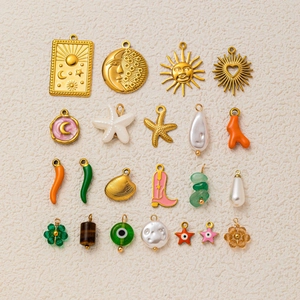 Flat lay of 21 gold-plated sun, moon, and chili pendants for DIY jewelry making