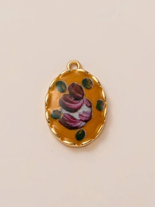 Close-up van ovale gouden hanger met oranje emaille en verfijnd bloemenpatroon
