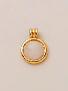 Detailopname van een 18K vergulde ronde hanger met een witte edelsteen in het midden