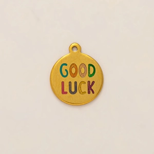 Dettaglio del ciondolo tartaruga tondo placcato oro 18K con scritta colorata Good Luck