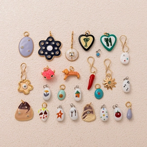 Detail verschiedener vergoldeter Emaille-Anhänger in Herz- und Tierform für DIY-Schmuck