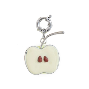 Detail of silver apple charm with cream enamel inlay and a large spring ring clasp