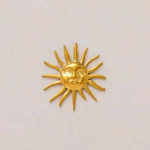 Dettaglio di un ciondolo a sole in oro 18 carati con volto a rilievo e raggi lucidi