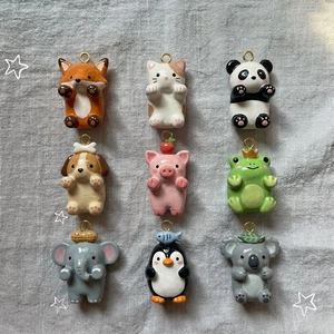 Vue macro de breloques animaux en céramique colorée dont chat et panda avec anneaux dorés