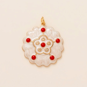 Détail macro d'un pendentif fleur en nacre avec perles rouges et finition dorée