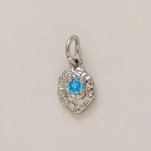 Macro detail of silver organic textured pendant with round blue gemstone setting
