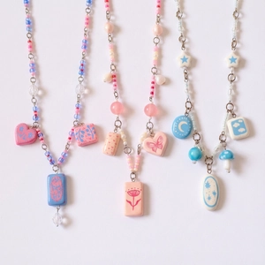 Detail of beaded Y2K necklaces with resin charms and pearls in pastel colors