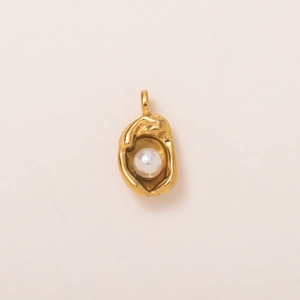 Detail van de vintage gouden hanger met centrale parel en getextureerde afwerking