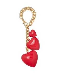 Detailed macro view of three glossy red heart charms hanging from a gold lobster clasp chain