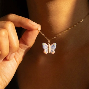 Golden butterfly necklace with pink and lavender enamel pendant on a model's neck