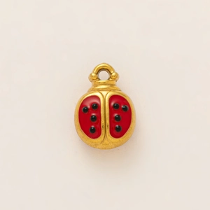 Macro detail of a 18k gold-plated ladybug pendant with red and black enamel finish