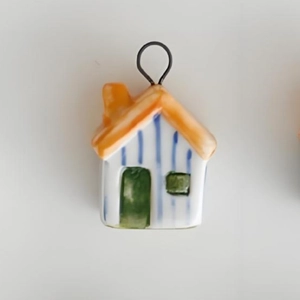 Detail of colorful ceramic house pendant with orange roof and 18K gold plated metal ring