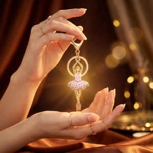 Eleganter goldener Ballett-Schlüsselanhänger mit rosa Strasskleid auf Seidenhintergrund