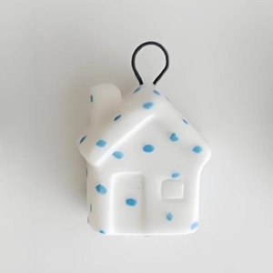 Detail showing white ceramic house pendant with blue hand-painted dots and metal ring