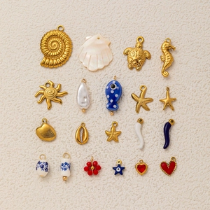 Flat lay view of ocean-themed 18k gold plated charms including sea shells and starfish