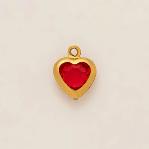Detail of a 18k gold-plated heart pendant with a faceted red gemstone center