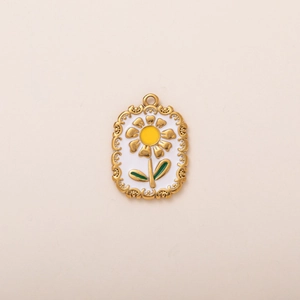 Detalle de un colgante de girasol vintage con filigrana dorada y esmalte blanco