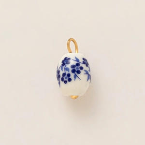 Detailed view of white ceramic pendant with blue floral pattern and gold plated hook