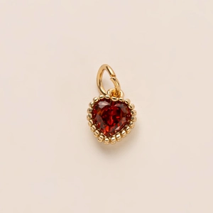 Elegant heart-shaped gold pendant featuring a deep red gemstone and beaded edge details