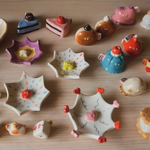 Cute handmade ceramic charms featuring mushroom, cake, and pudding food shapes on wood