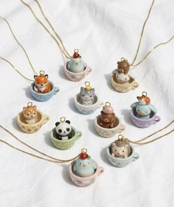 Dettaglio di vari ciondoli in ceramica con animali in tazze da tè fiorite su catene d'oro