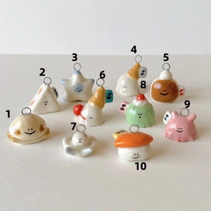 Macro view of ten cute ceramic charms including fruit and teapot shapes with metal rings