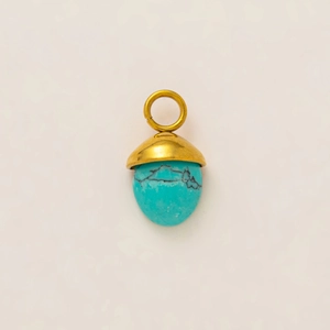 Détail macro d'un pendentif gland en turquoise avec calotte et anneau plaqués or 18k