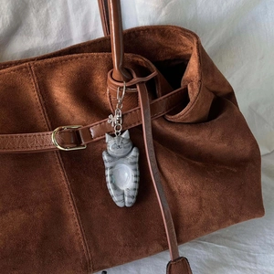 Ciondolo gatto a strisce grigie con quadrifoglio appeso a una borsa tote in pelle