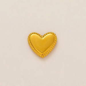 Vue détaillée du pendentif coeur plaqué or 18k avec bord perlé sur fond beige clair