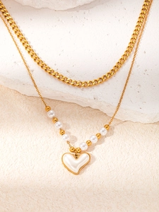 Dettaglio della collana a doppio strato in acciaio dorato con pendente a cuore e perle