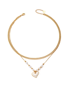 Dettaglio di collana a doppio strato dorata con ciondolo a cuore e perle
