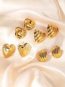 Vue détaillée de boucles d'oreilles rétro en acier titane doré sur tissu en soie satinée