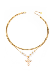 Dettaglio di collana doppia dorata con catena a maglia e ciondolo a croce di perle