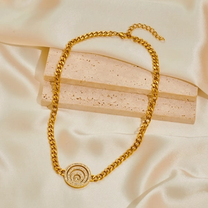 Gold Cuban chain necklace with zircon-encrusted spiral pendant on beige silk