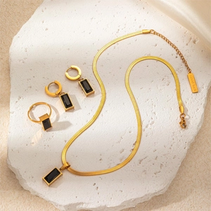 Detail view of gold titanium steel jewelry set with black rectangular gemstones and lucky tag