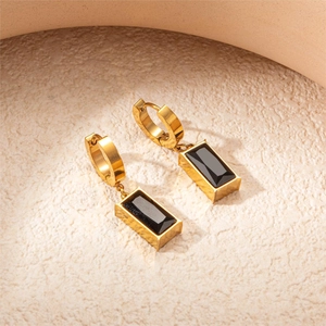 Detail of titanium steel earrings with golden hoops and black rectangular pendants