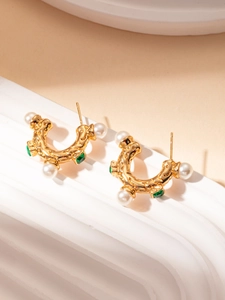 Détail de boucles d'oreilles dorées à texture lave avec perles et pierres vertes